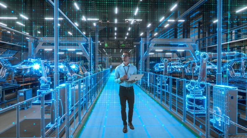 Ingenieur mit Laptop in einer digital überlagerten Roboterfertigung